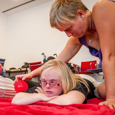 Eine Person massiert eine andere Person mit einem Igelball.